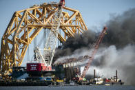 Fire fighters spray water into the cut away mid-section of the cargo vessel Golden Ray, Friday, May 14, 2021, Brunswick, Ga. The Golden Ray had roughly 4,200 vehicles in its cargo decks when it capsized off St. Simons Island on Sept. 8, 2019. Crews have used a giant gantry crane to carve the ship into eight giant chunks, then carry each section away by barge. (AP Photo/Stephen B. Morton)