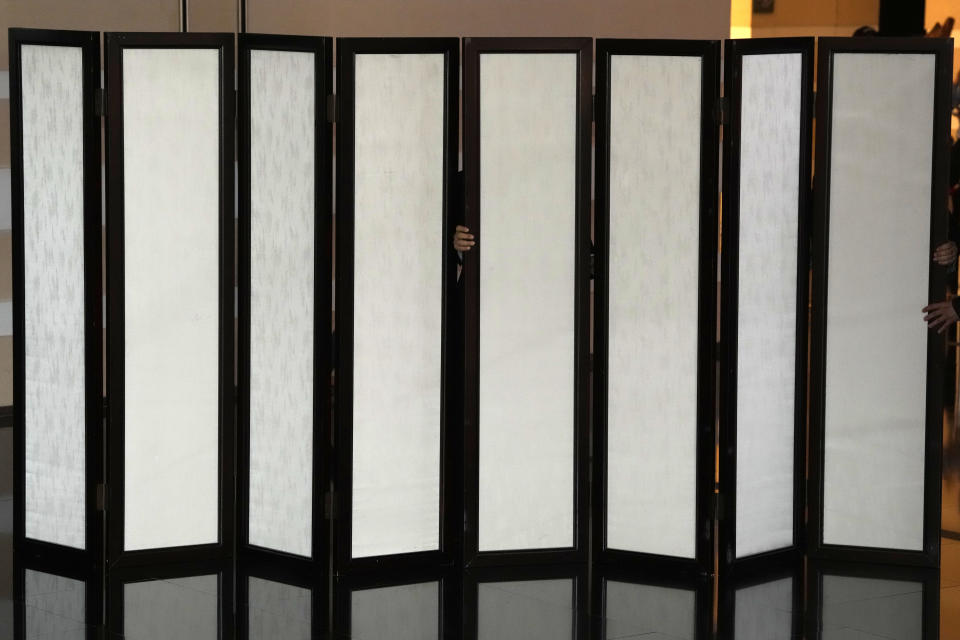 A hand is seen between screens setup to block the view of journalists at the lobby of the hotel where U.S. Secretary of State Antony Blinken is staying in Beijing, Sunday, June 18, 2023. (AP Photo/Ng Han Guan)