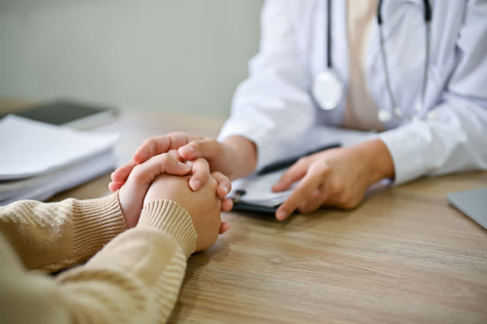 manos de mujer entrelazadas en el médico