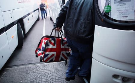 A man carrying a bag adorned with a British Union Jack flag steps into a bus departing from Sofia's central bus station to London via Austria, Germany and France January 2, 2014. REUTERS/Stoyan Nenov