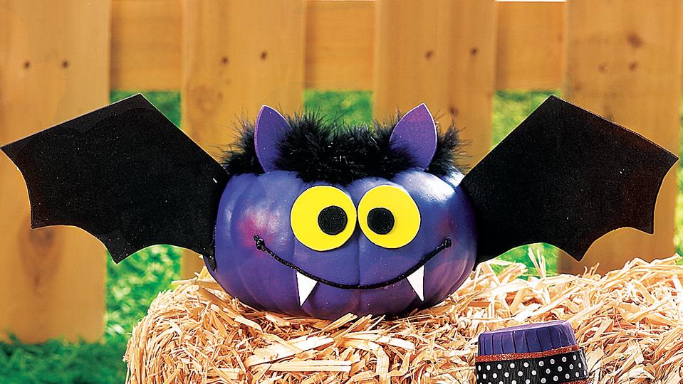 Pumpkin face painted and decorated to look like a bat with wings 