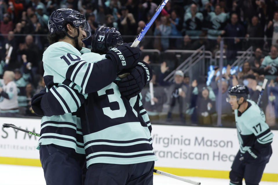 Seattle Kraken center Matty Beniers (10) hugs center Yanni Gourde (37) after Gourde scored a goal against the Boston Bruins during the second period of an NHL hockey game Thursday, Feb. 23, 2023, in Seattle. (AP Photo/John Froschauer)