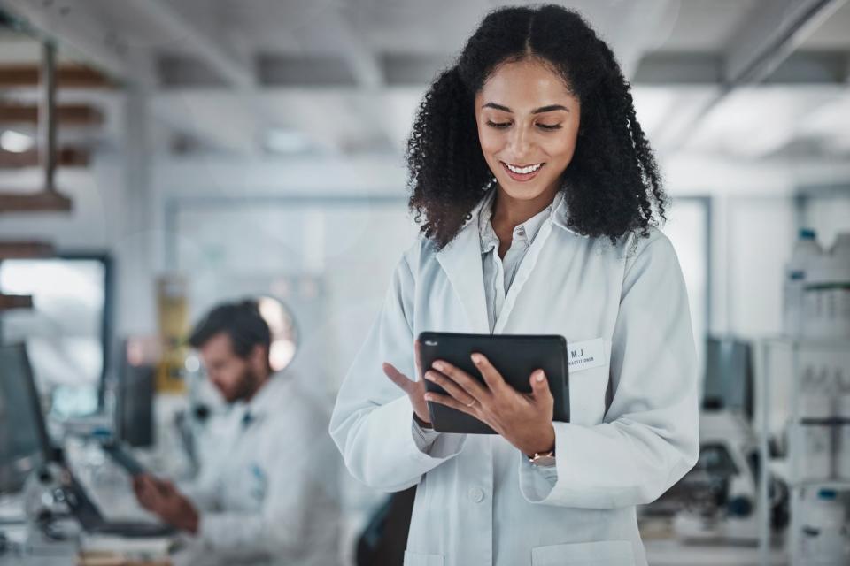 A scientist looks at something on a tablet in a lab.