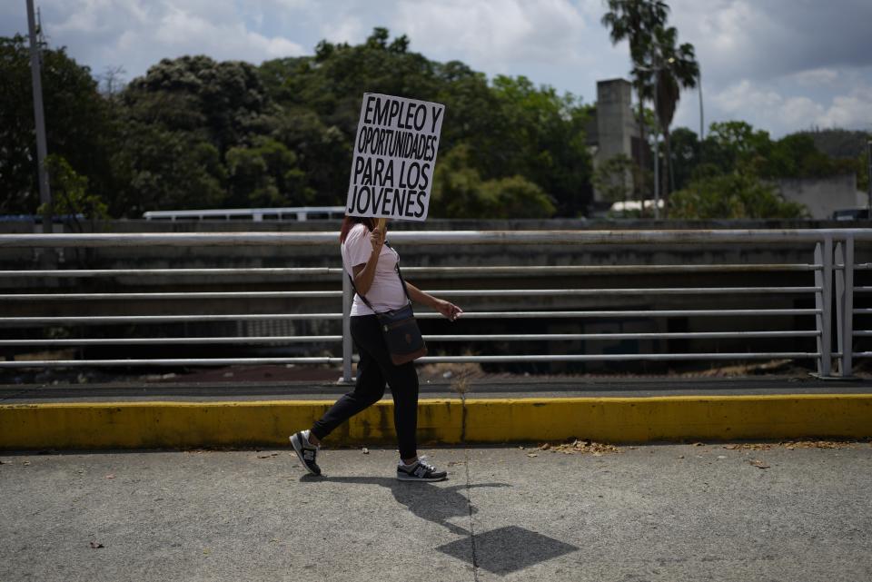 Una mujer lleva un cartel que pide oportunidades laborales en una marcha por el Día Internacional de la Mujer en Caracas, Venezuela, el miércoles 8 de marzo de 2023. (AP Foto/Ariana Cubillos)