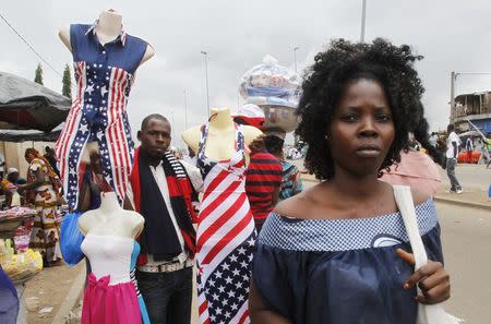 A street vendor holds mannequins wearing clothes depicting the U.S. national flag in the streets of Abidjan August 3, 2014. REUTERS/Luc Gnago