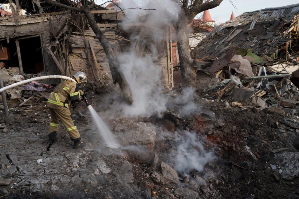 Firefighters extinguish a fire next to houses destroyed during a Russian attack on Kyiv (AP)