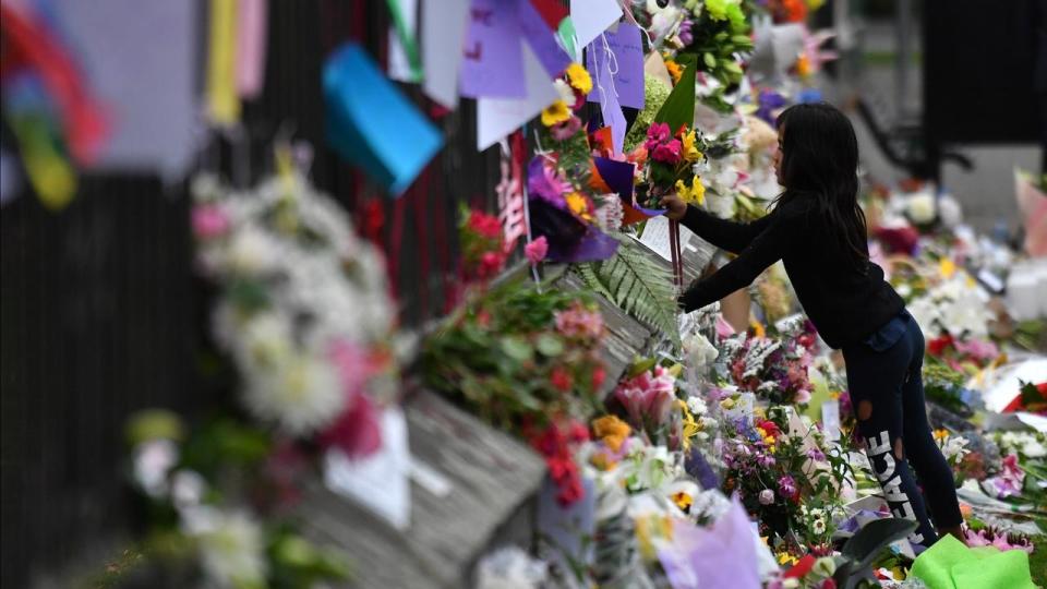 A child places flowers at a makeshift memorial for the victims of the mosque mass murders. Source: AAP