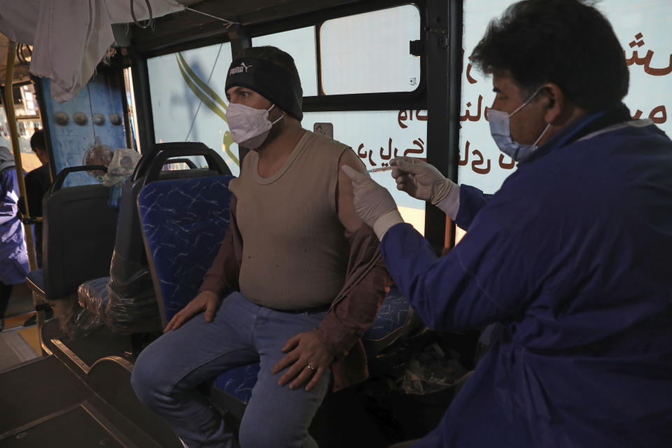 A man receives a COVID-19 vaccine at a mobile vaccine clinic bus at the Grand Bazaar of Tehran, Iran, Saturday, Jan. 22, 2022. After successive virus waves pummeled the country for nearly two years, belated mass vaccination under a new, hard-line president has, for a brief moment, left the stricken nation with a feeling of apparent safety. (AP Photo/Vahid Salemi)