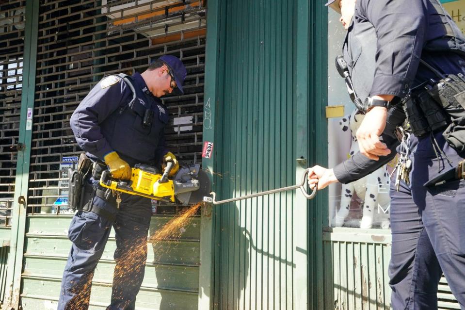An NYPD officer uses a saw to cut through a padlock at the locked Zaza Waza store on Columbus Ave. in Manhattan on March 14, 2024. Robert Miller