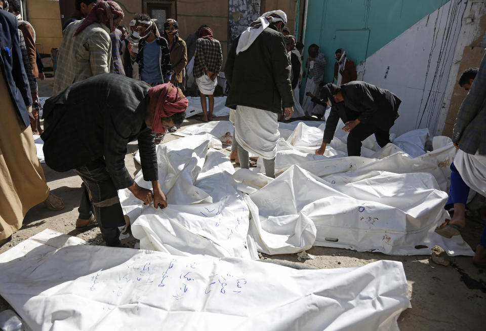 People look at the covered bodies of people that died in a Saudi-led coalition airstrike that killed at least 87 people, in a stronghold of Houthi rebels on the border with Saudi Arabia, in the northern Saada province of Yemen, Saturday, Jan. 22, 2022. Internet access remained largely down on Sunday after another Saudi-led coalition airstrike hit a telecommunications center Friday at the Red Sea port city of Hodeida. (AP Photo/Hani Mohammed)