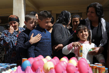 Believers wait to receive a painted egg during celebrations after the Easter Mass in Mar Gewargis (St George) Chaldean Catholic church, which was damaged by Islamic State militants, in the town of Tel Esqof, Iraq, April 16, 2017. REUTERS/Marko Djurica