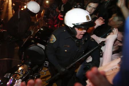 A police officer riding a motorcycle confronts a group of protesters after being surrounded during a demonstration against the grand jury decision in the Ferguson, Missouri shooting of Michael Brown in San Francisco, California November 28, 2014. REUTERS/Stephen Lam