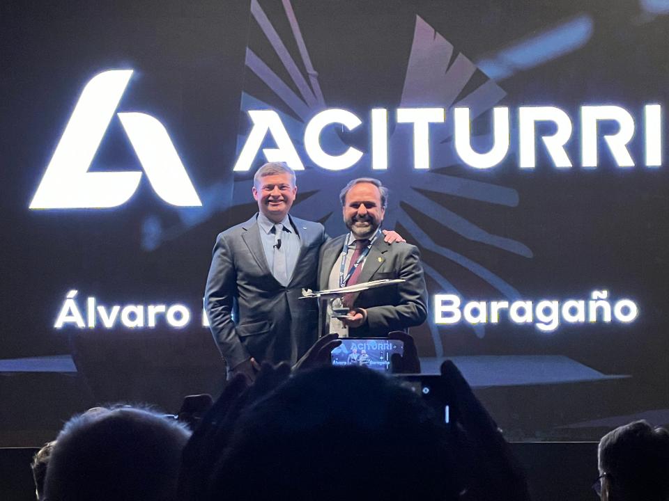 Boom CEO Blake Scholl and the Aciturri rep hold an Overture model on stage at Paris Air Show