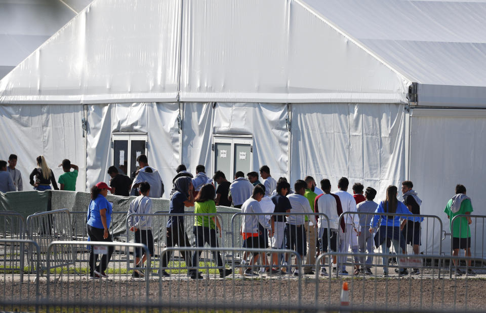 FILE- In this Feb. 19, 2019 file photo, children line up to enter a tent at the Homestead Temporary Shelter for Unaccompanied Children in Homestead, Fla. The American Civil Liberties Union is seeking potentially millions of dollars in damages on behalf of thousands of immigrant families who were separated at the U.S.-Mexico border. The ACLU and other attorneys filed a lawsuit Thursday, Oct. 3, 2019, against past and present Trump administration officials in federal court in Tucson alleging the government violated immigrants' rights and traumatized young children who were taken from their parents after crossing the border illegally. (AP Photo/Wilfredo Lee, File)