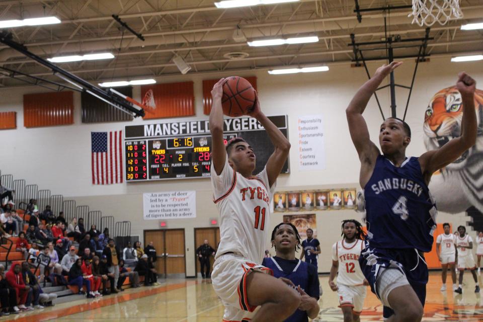 Mansfield Senior's Nathaniel Haney attacks the rim as Sandusky's De'Mar Moore looks to make a block during the Tygers' 79-74 loss.