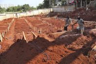 Workers take a rest after digging graves at the special section of Jombang Public Cemetery reserved for those who died of COVID-19, in Tangerang, on the outskirts of Jakarta, Indonesia, Wednesday, Aug. 4, 2021. Indonesia surpassed 100,000 confirmed COVID-19 deaths on Wednesday, a grim milestone in a country struggling with its worst pandemic wave fueled by the delta variant, amid concerns the actual figure could be much higher. (AP Photo/Tatan Syuflana)