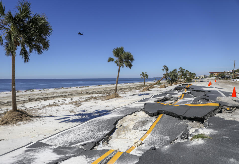 A helicopter flies along the coast as a portion of Highway 98 is seen crumbled Friday, Oct. 12, 2018 in Mexico Beach, Fla. Residents of the small beach town of Mexico Beach began to make their way back to their homes some for the first time after Hurricane Michael made landfall Wednesday. (Chris Urso/The Tampa Bay Times via AP)