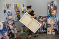 Visual artist Yoko Nishio carries a painting amid her series titled "Indexados," inside her studio during the COVID-19 pandemic in Rio de Janeiro, Brazil, Saturday, March 27, 2021. Nishio said the series Indexes is about virtual human relationships and is painted on vertical canvases to mimic cell phones. (AP Photo/Bruna Prado)