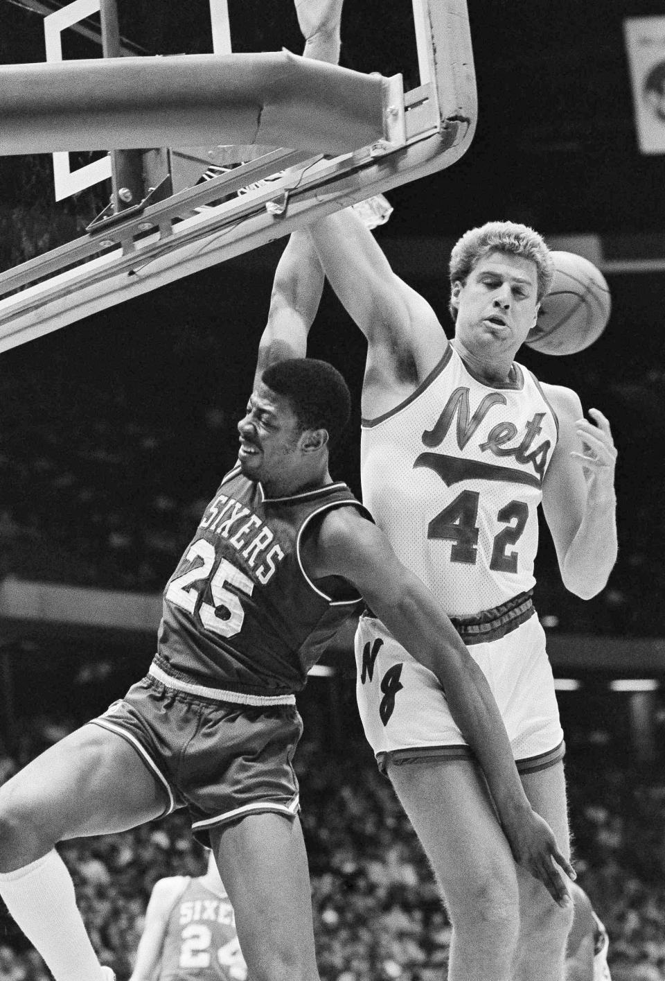 FILE - The ball bounces away as Philadelphia 76ers' Earl Cureton (25) and New Jersey Nets' Mike Gminski (42) clash for a rebound during the first period of an NBA basketball game at Meadowlands Arena in East Rutherford, N.J., April 15, 1983. It was the last home game of the regular season for the Nets. Cureton, who won two NBA championships in 12 seasons in the league, died Sunday, Feb. 4, 2024. He was 66. (AP Photo/Ron Frehm, File)