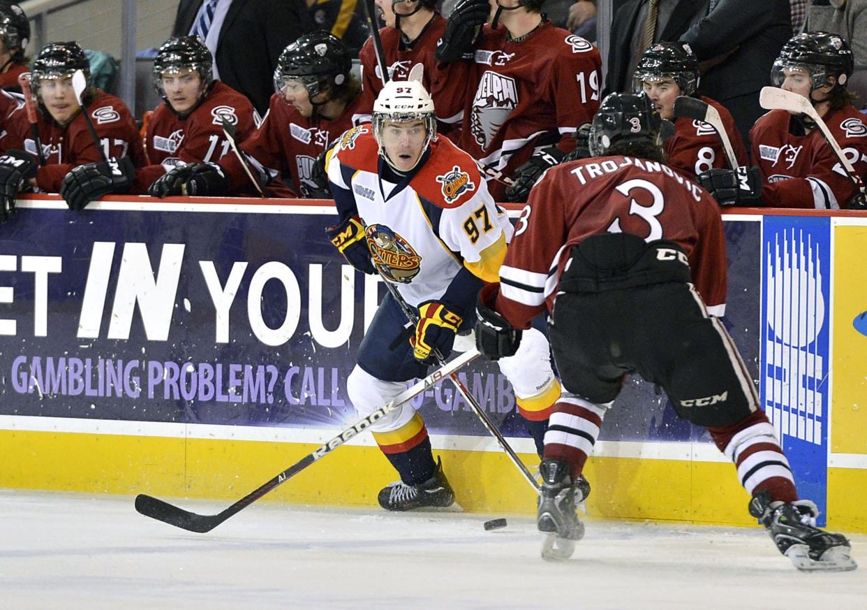 In this Nov. 28, 2013, file photo, the Erie Otters' Connor McDavid defends the puck from Guelph Storm's Steven Trojanovic in front of the Guelph bench during the third period of an OHL game at Erie Insurance Arena on Thanksgiving Day.