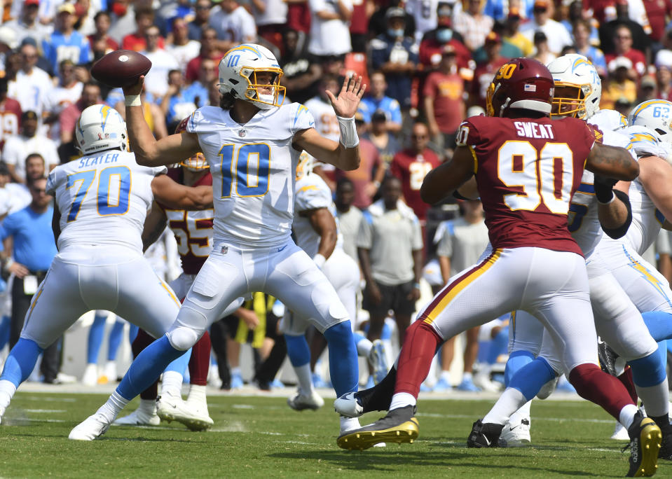 Sep 12, 2021; Landover, Maryland, USA; Los Angeles Chargers quarterback Justin Herbert (10) attempts a pass as Washington Football Team defensive end Montez Sweat (90) rushes during the first quarter at FedExField. Mandatory Credit: Brad Mills-USA TODAY Sports