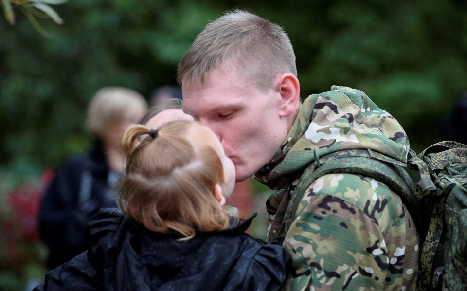 A Russian reservist bids his child farewell before his departure for a base in the course of partial mobilization of troops - Stringer/REUTERS