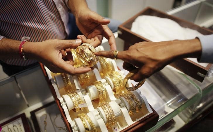 An employee shows gold bangles to a customer at a jewellery showroom on the occasion of Dhanteras at a market in Mumbai November 1, 2013. REUTERS/Danish Siddiqui/Files