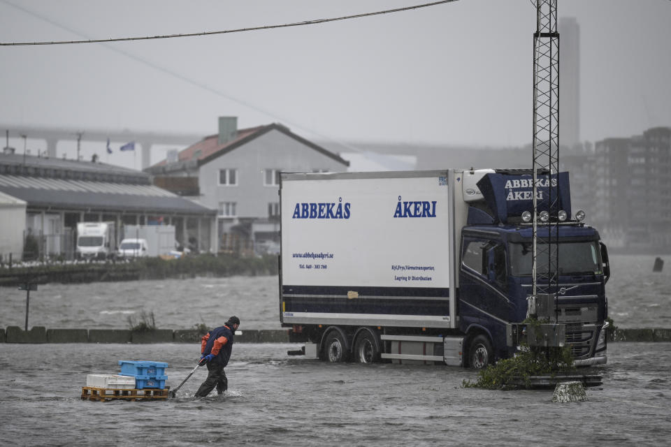 A man walks along the flooded Fiskhamnen (fishing port) after the Gota Alv river overflowed following heavy raining in Gothenburg, Sweden, Tuesday, Aug. 8, 2023. (Björn Larsson Rosvall/TT News Agency via AP)