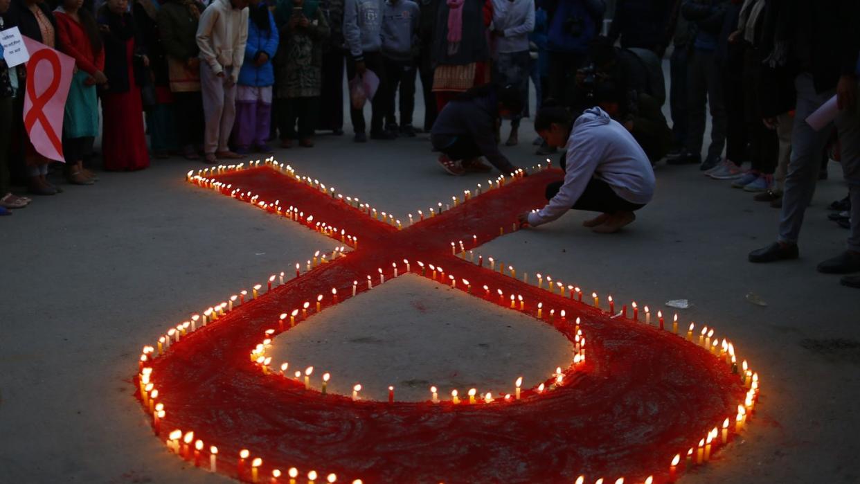 Aktivisten stellen auf einer Veranstaltung im Vorfeld des Welt-Aids-Tags Kerzen auf, die eine rote Schleife formen - ein weltweit anerkanntes Symbol für die Solidarität mit HIV-Infizierten.