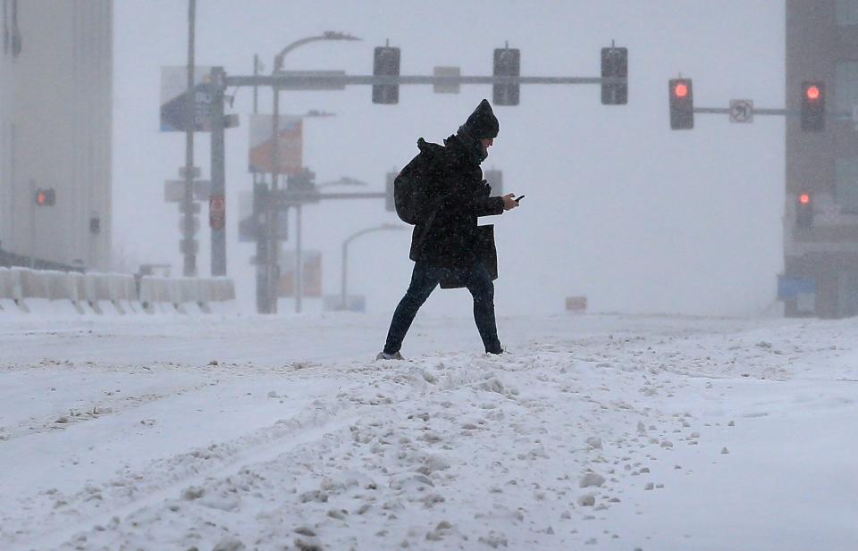 A pedestrian crosses Market Street during a snow storm in downtown St. Louis on Monday, Feb. 15, 2021. The brutally cold weather is expected to continue through Saturday with more snow in the forecast for Wednesday and Thursday. (David Carson/St. Louis Post-Dispatch via AP)