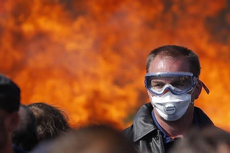 A striking French labour union employee stands near a burning barricade during a police operation to free up a fuel depot near the Donges oil refinery as workers protest the labour reforms law proposal in Donges, France, May 27, 2016. REUTERS/Stephane Mahe