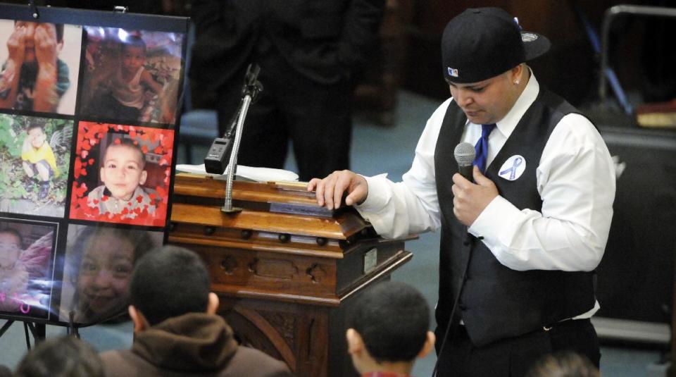 Jose Oliver, left, father of five-year-old Jeremiah Oliver, stands next to a display of photographs as he speaks during his son's funeral service at Rollstone Congregational Church in Fitchburg, Mass., on Saturday, May 3, 2014. Jeremiah Oliver is the 5-year-old Fitchburg boy who disappeared in September 2013 and was found dead along Interstate 190 in Sterling, Mass., in April. (AP Photo/Worcester Telegram & Gazette, Paul Kapteyn)