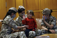 Members of the Lebanese General Security forces play with an Albanian child during an operation to take them back home to Albania from al-Hol, northern Syria, at the Rafik Hariri International Airport in Beirut, Lebanon, Tuesday, Oct. 27, 2020. The repatriation of four children and a woman related to Albanian nationals who joined Islamic extremist groups in Syria "is a great step" to be followed by more repatriations, Albania's prime minister said Tuesday. (AP Photo/Bilal Hussein)