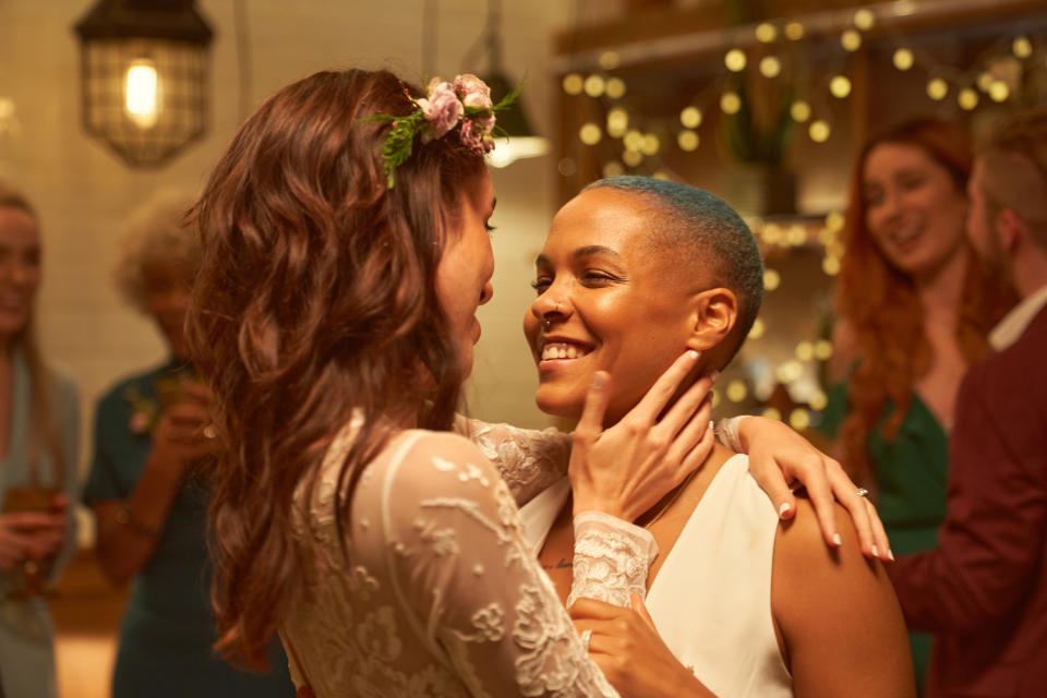 Two lesbians on their wedding day smiling and staring at each other with awe.