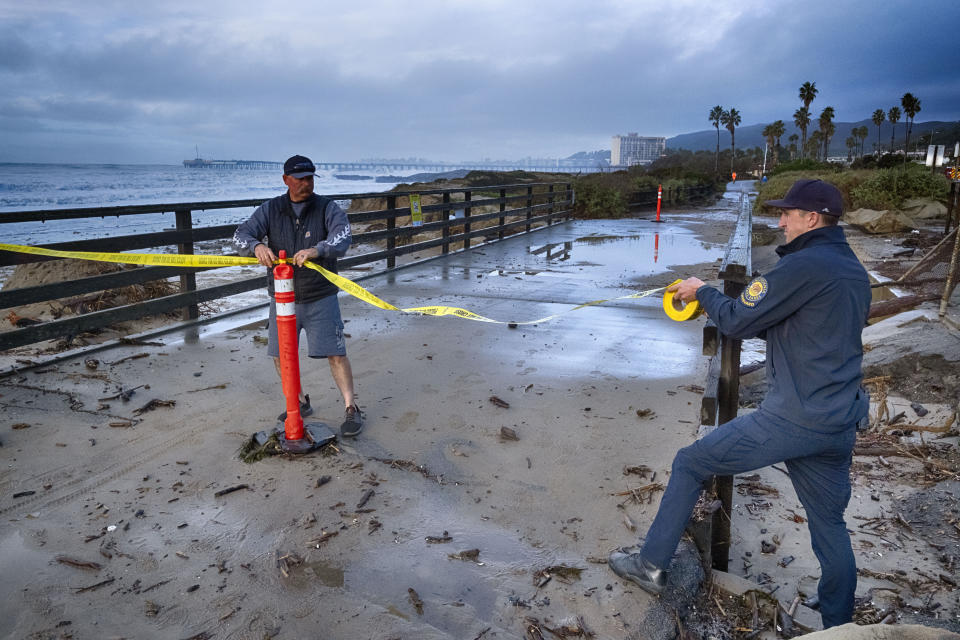 Ventura city workers close off an ocean walk where turbulent surf was hitting on Saturday, Dec. 30, 2023 in Ventura, Calif. Bulldozers built giant sand berms to protect beachfront homes in Ventura, one of California's coastal cities hit hard this week by extraordinary waves generated by powerful swells from Pacific storms. (AP Photo/Richard Vogel)