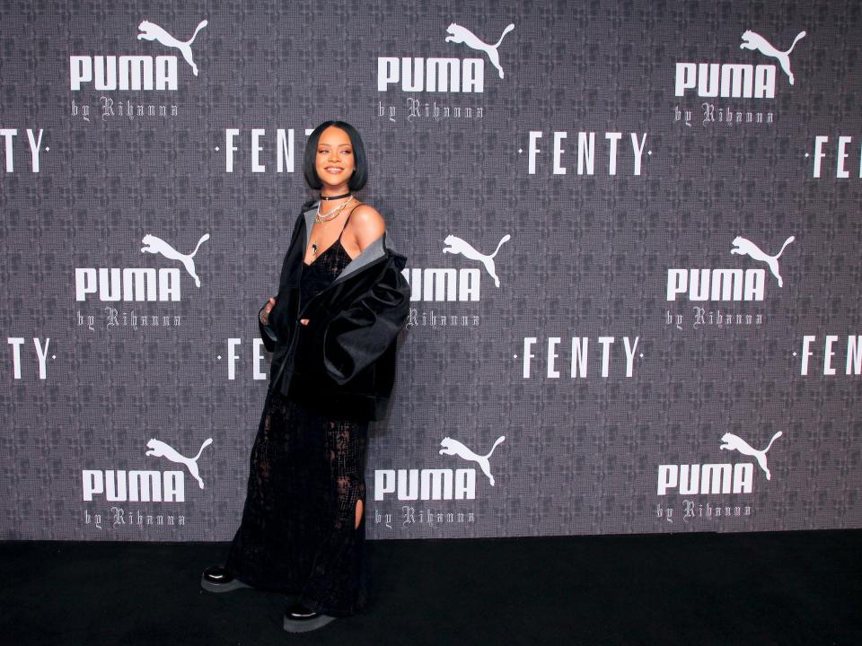 Rihanna stands in front of Puma and Fenty wall at fashion show