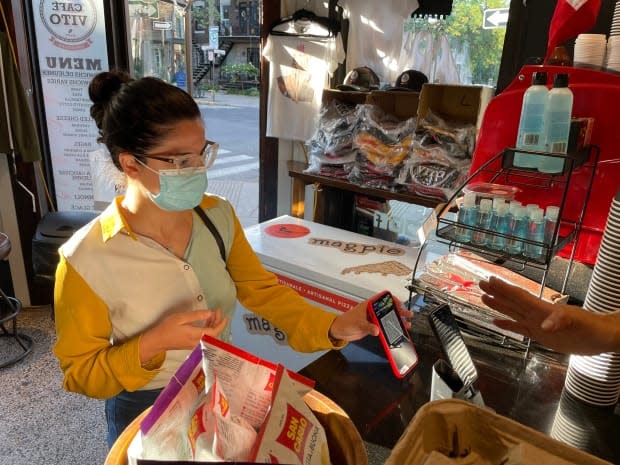 A customer scans her vaccination passport in at a café in Montreal's Villeray neighbourhood on Wednesday. Quebec's vaccine passport system has gone into effect and will be enforced on Sept. 15.   (Alex Leduc/CBC - image credit)