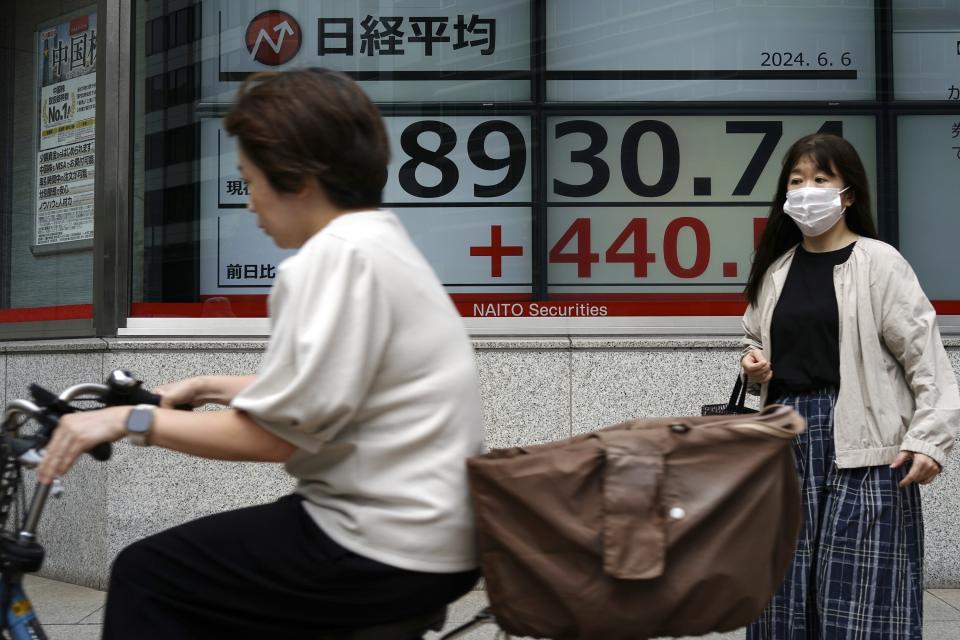 People pass by an electronic stock board showing Japan's Nikkei 225 index at a securities firm Thursday, June 6, 2024, in Tokyo. (AP Photo/Eugene Hoshiko)