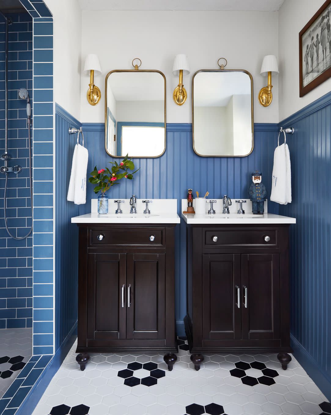 bathroom with blue subway tile in the shower, blue paint on the wainscoting and oversized black and white hex tiles