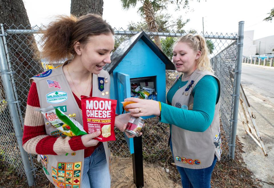 Girl Scout Caitlin Holmes, right, put up her service project, a food pantry box, to serve the homeless and people in need on Dec. 4, 2021. The box is located on Beach Drive, near the Panama City Marina. Fellow scout Lara Murphy helped Holmes stock the box.