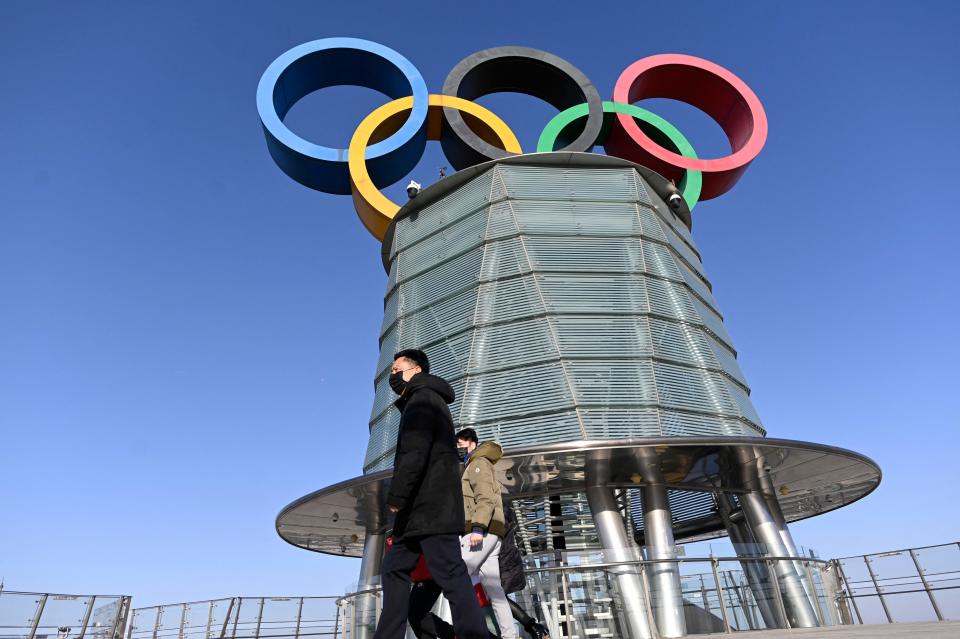 A group of people pose in front of the Beijing Olympic tower.