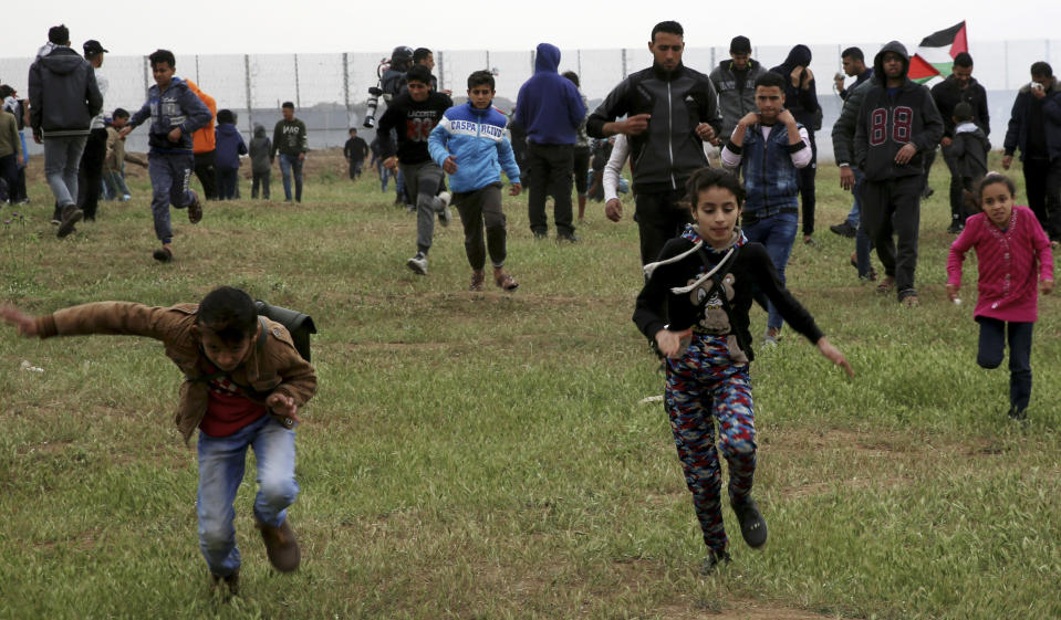 Protesters run to cover from teargas fired by Israeli troops near fence of Gaza Strip border with Israel, marking first anniversary of Gaza border protests east of Gaza City, Saturday, March 30, 2019. Tens of thousands of Palestinians on Saturday gathered at rallying points near the Israeli border to mark the first anniversary of weekly protests in the Gaza Strip, as Israeli troops fired tear gas and opened fire at small crowds of activists who approached the border fence. (AP Photo/Adel Hana)