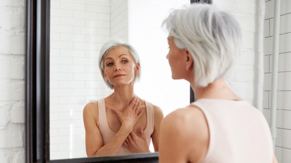 mature woman doing an at-home health screening test on her skin while looking in the mirror