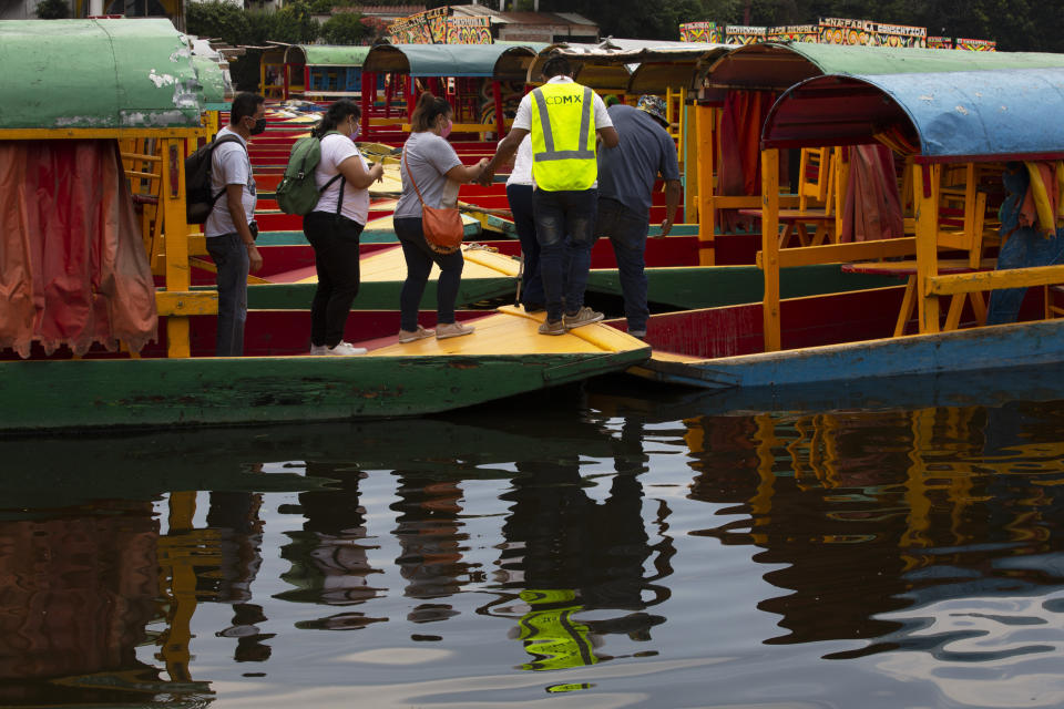 A group board one of the painted wooden boats, known as trajineras, popular with tourists that ply the water canals in the Xochimilco district of Mexico City, after all activities had been on pause for the past six months due to the COVID-19 pandemic. (AP Photo/Marco Ugarte)