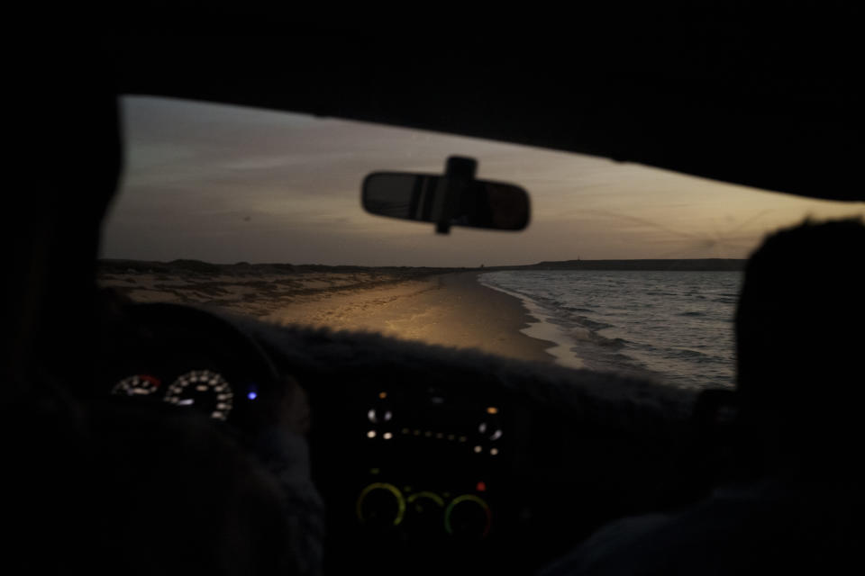 Una playa es iluminada por los faros de un auto al atardecer cerca de Nuadibú, Mauritania, el 25 de noviembre de 2021. (AP Foto/Felipe Dana)