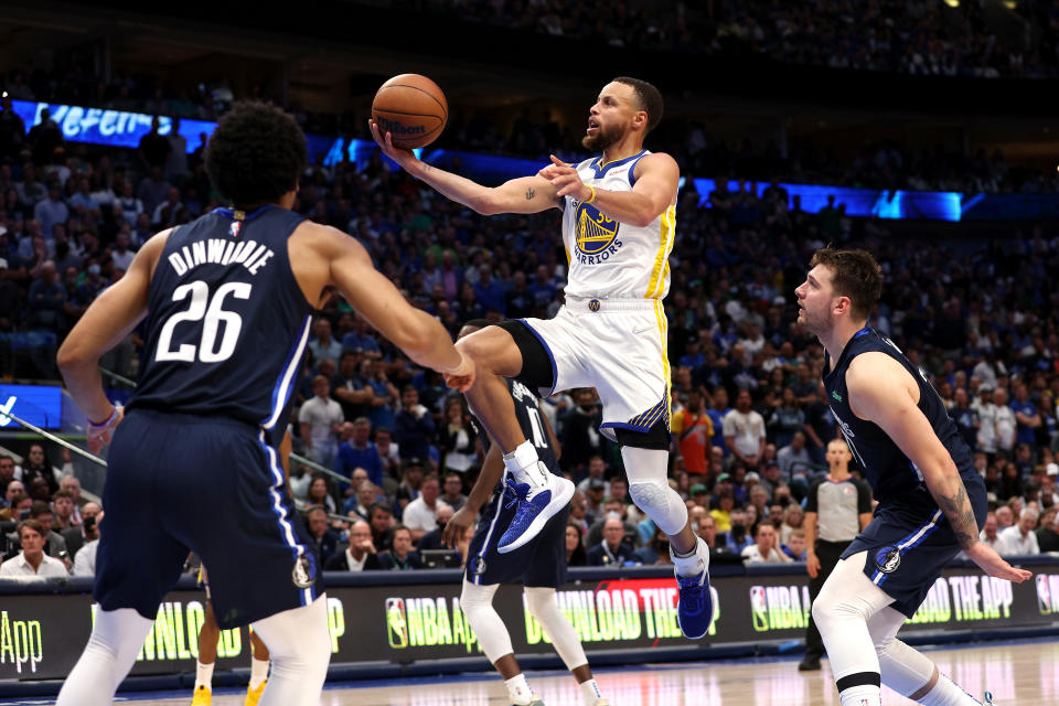 DALLAS, TEXAS - MAY 22: Stephen Curry #30 of the Golden State Warriors drives to the basket against Spencer Dinwiddie #26 and Luka Doncic #77 of the Dallas Mavericks during the fourth quarter in Game Three of the 2022 NBA Playoffs Western Conference Finals at American Airlines Center on May 22, 2022 in Dallas, Texas. NOTE TO USER: User expressly acknowledges and agrees that, by downloading and or using this photograph, User is consenting to the terms and conditions of the Getty Images License Agreement. (Photo by Tom Pennington/Getty Images)