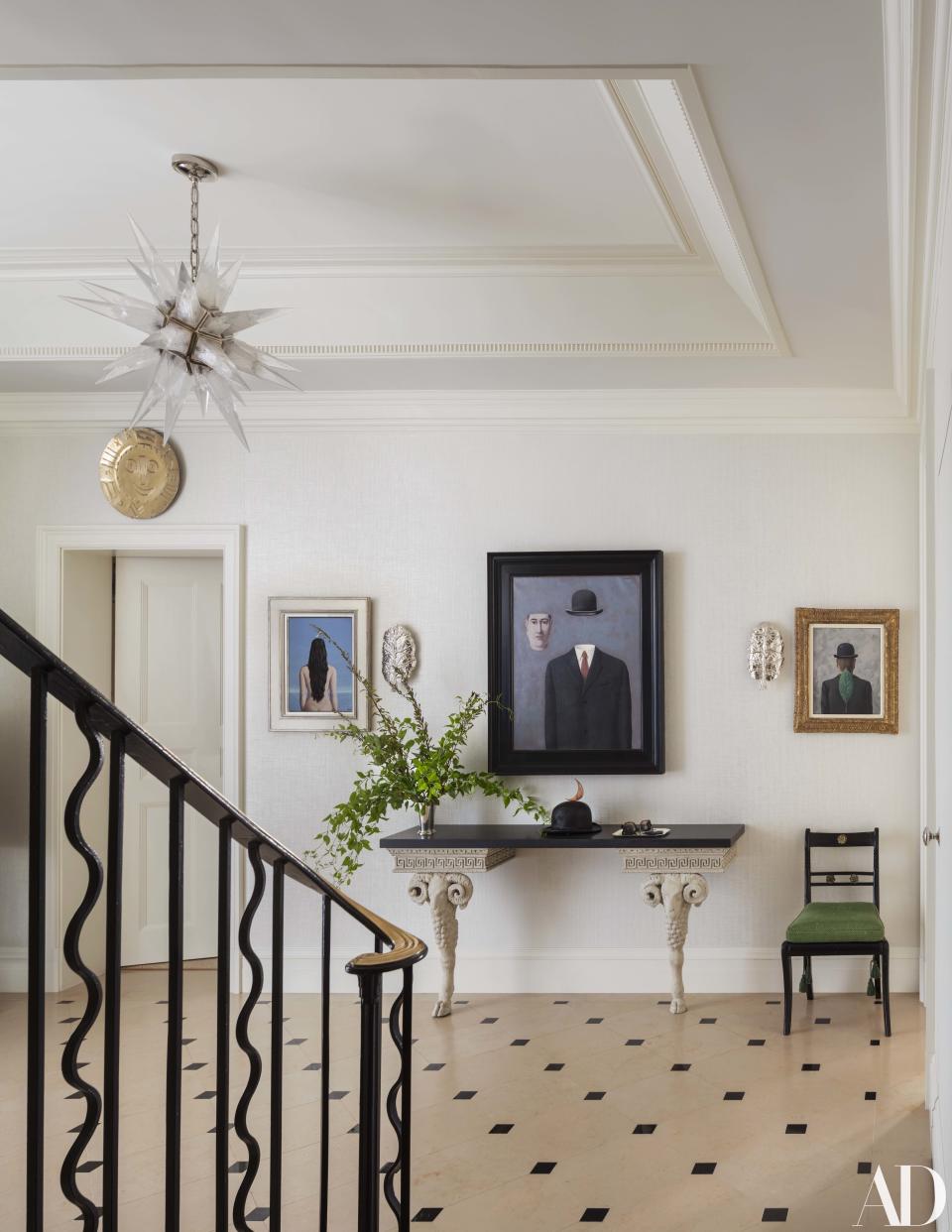 The entry features three Magritte paintings over a pair of antique consoles that Buatta joined with a new stone top.