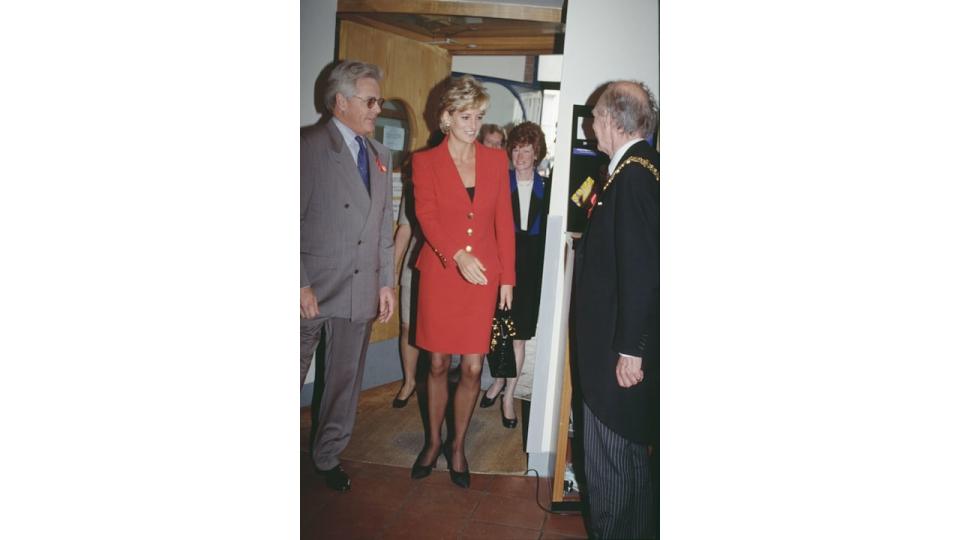 Princess Diana in a red suit meeting people at London Lighthouse