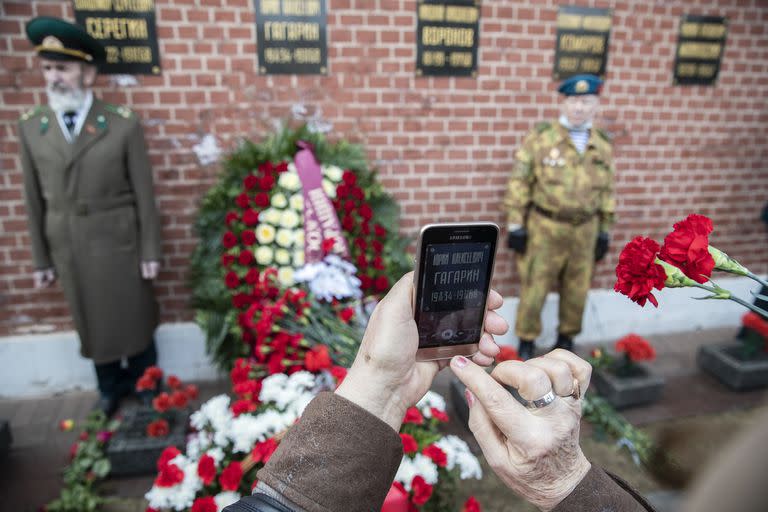 Una mujer toma una foto de la tumba de Yuri Gagarin, la primera persona que voló al espacio, en el muro del Kremlin, mientras la gente llega a depositar flores en Moscú, Rusia