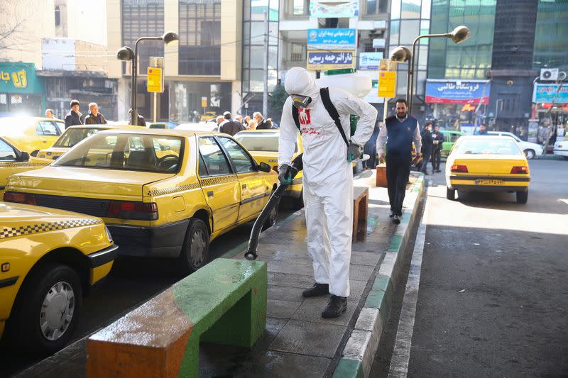 A member of the medical team wears a protective face mask, following the coronavirus outbreak, as he sprays disinfectant liquid to sanitise a taxi station in Tehran